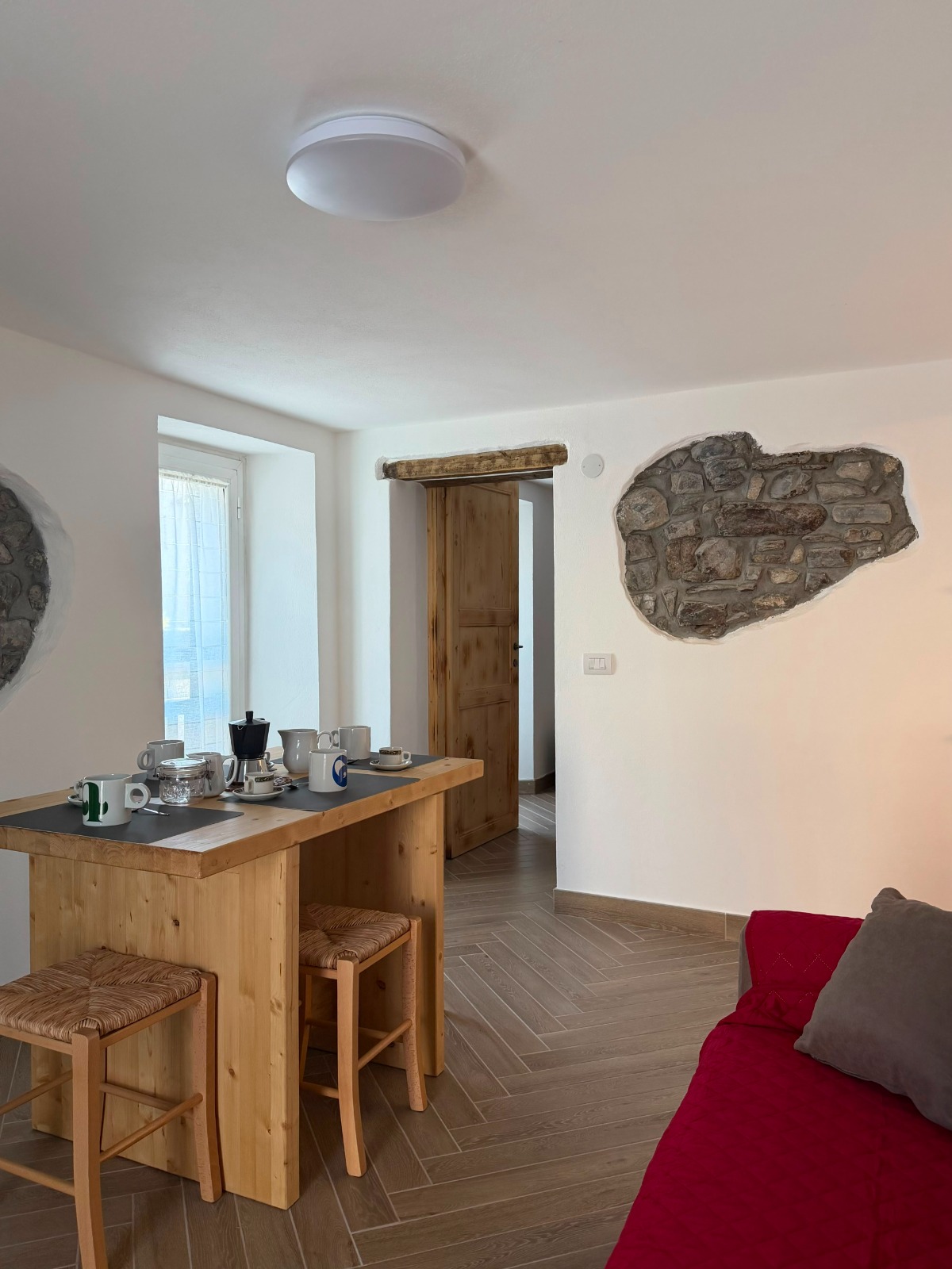 Zona giorno con tavolo in legno e pareti in pietra