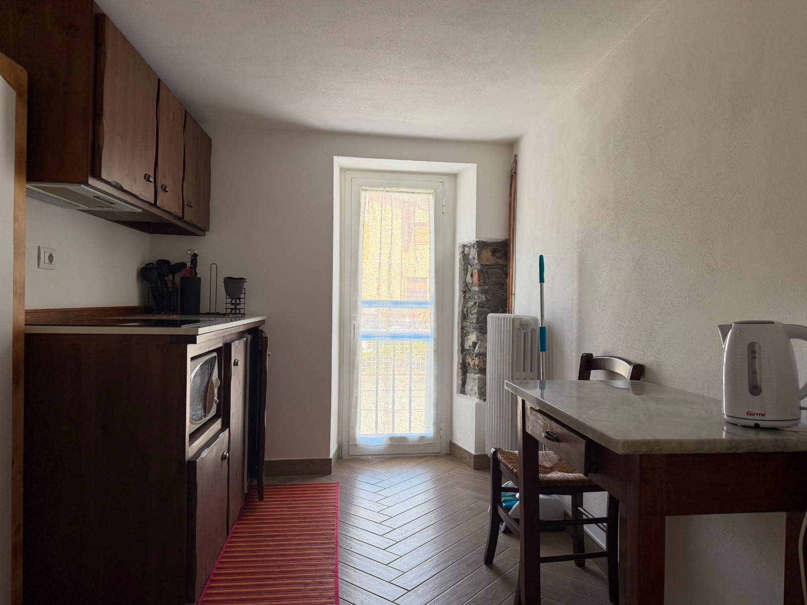 Cucina con tavolo e porta finestra sul balcone